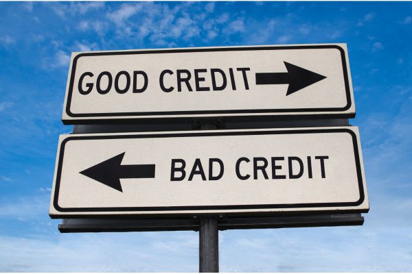 A road sign with two panels: "GOOD CREDIT" points right, and "BAD CREDIT" points left, against a blue sky.