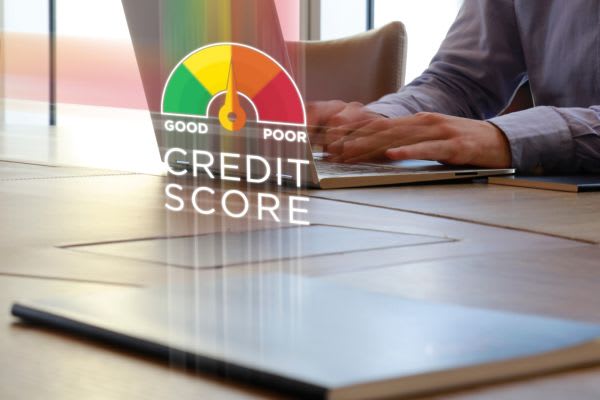 A credit score meter is digitally projected above a laptop, with hands typing on the keyboard.