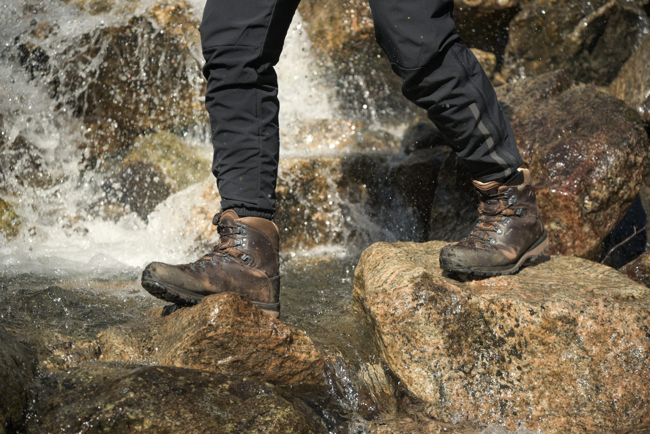 Person with proper mountain boots crossing a river