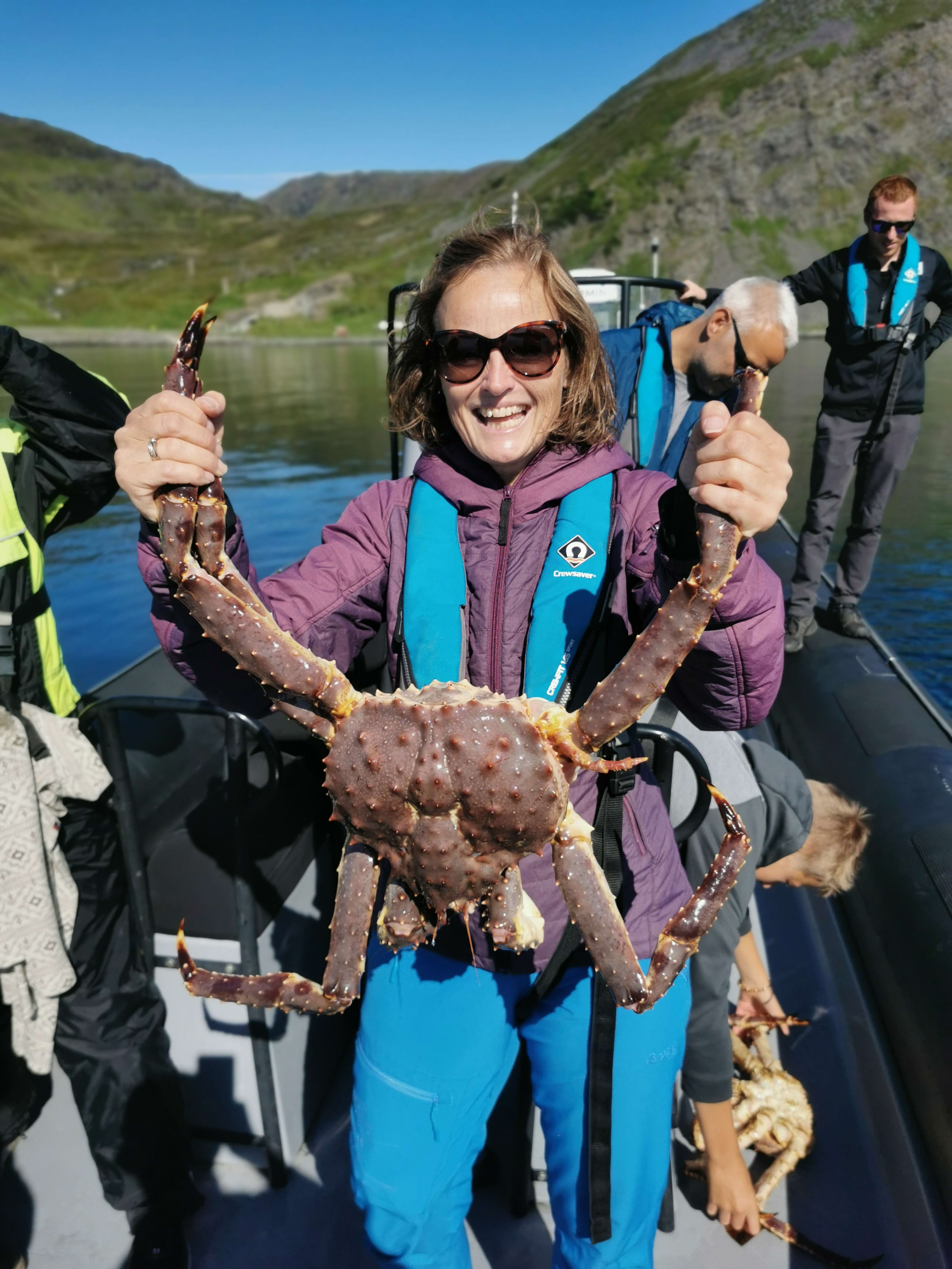 Woman holding up king crab caught outside Honningsvåg