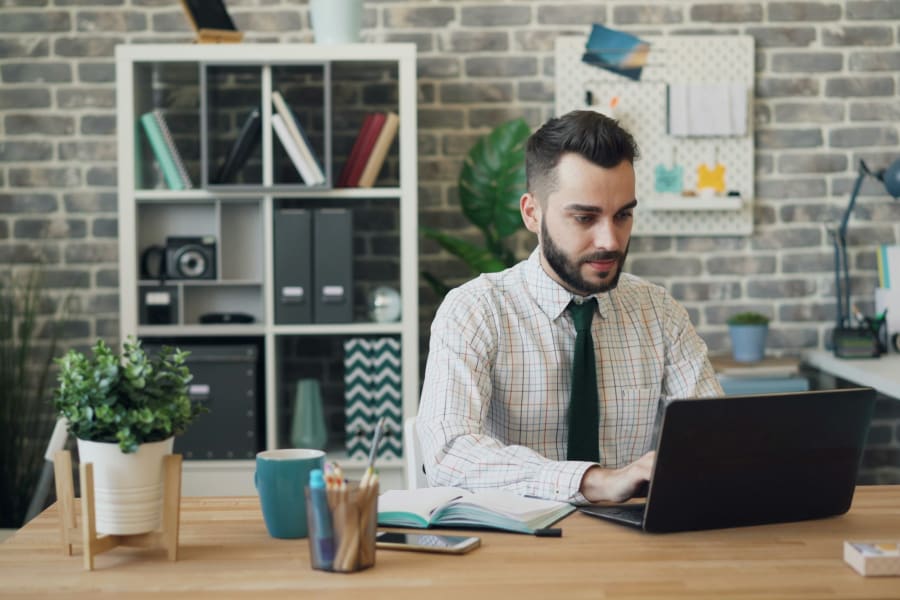 A friendly accountant working at her desk, smiling at a laptop