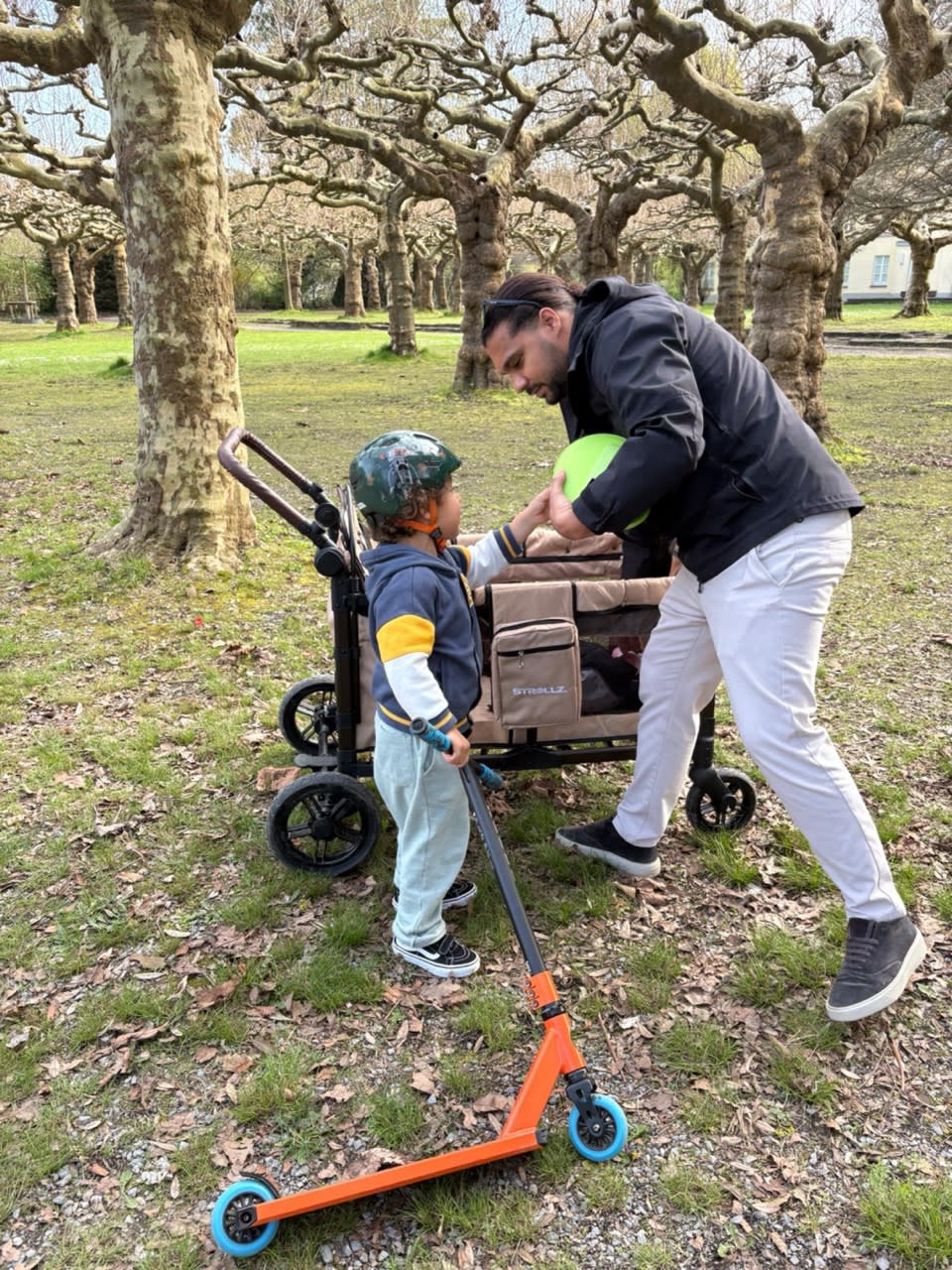Parent and child enjoying a day outdoors with a STROLLZ. stroller wagon in the park.
