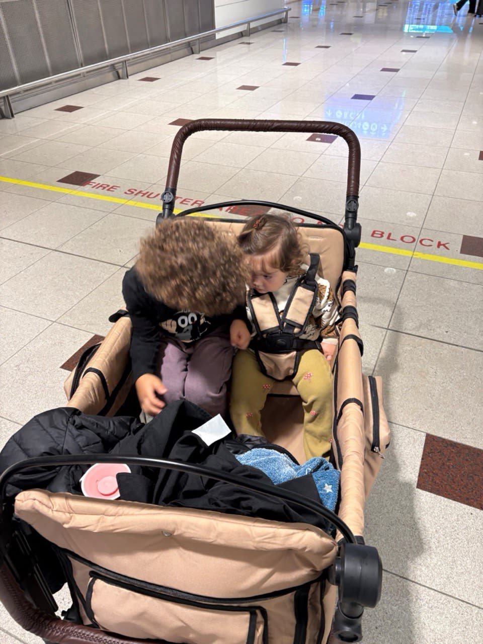 Children travelling comfortably in a STROLLZ. stroller wagon at the airport.