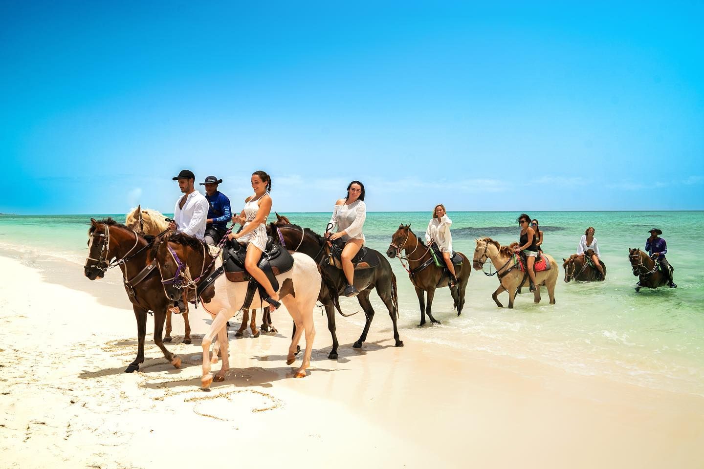 Guests on horseback in the turquoise water at Blue Hills