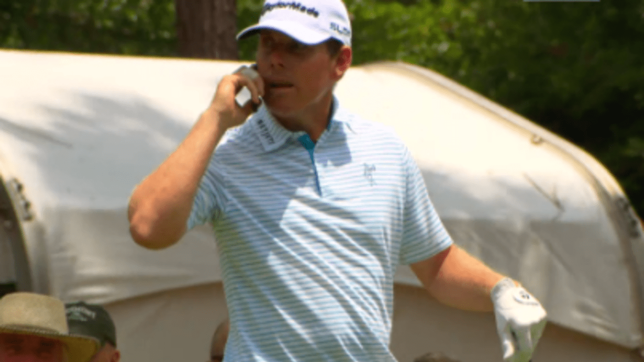 Justin Leonard telefoniert auf der Proberunde der US Open mit dem Handy eines Volunteers.