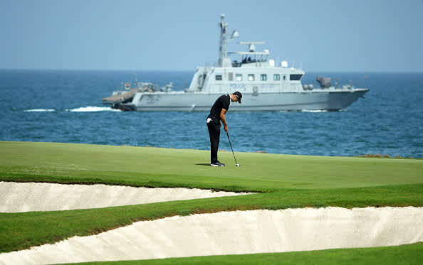 MUSCAT, OMAN - MARCH 01: Martin Kaymer of Germany putts on the 9th as the Police Patrol Boat passes by during Day Four of the Oman Open at Al Mouj Golf Complex on March 01, 2020 in Muscat, Oman. (Photo by Warren Little/Getty Images)