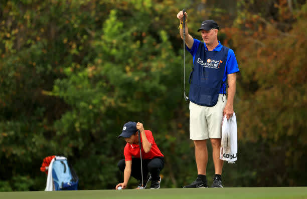 ORLANDO, FLORIDA - DECEMBER 20: Tiger Woods of the United States' son Charlie Woods line up a putt with caddie Joe LaCava on the 15th hole during the final round of the PNC Championship at the Ritz Carlton Golf Club on December 20, 2020 in Orlando, Florida. (Photo by Mike Ehrmann/Getty Images)