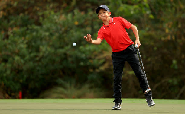 ORLANDO, FLORIDA - DECEMBER 20: Tiger Woods of the United States' son Charlie Woods tosses a ball on the 16th hole during the final round of the PNC Championship at the Ritz Carlton Golf Club on December 20, 2020 in Orlando, Florida. (Photo by Mike Ehrmann/Getty Images)
