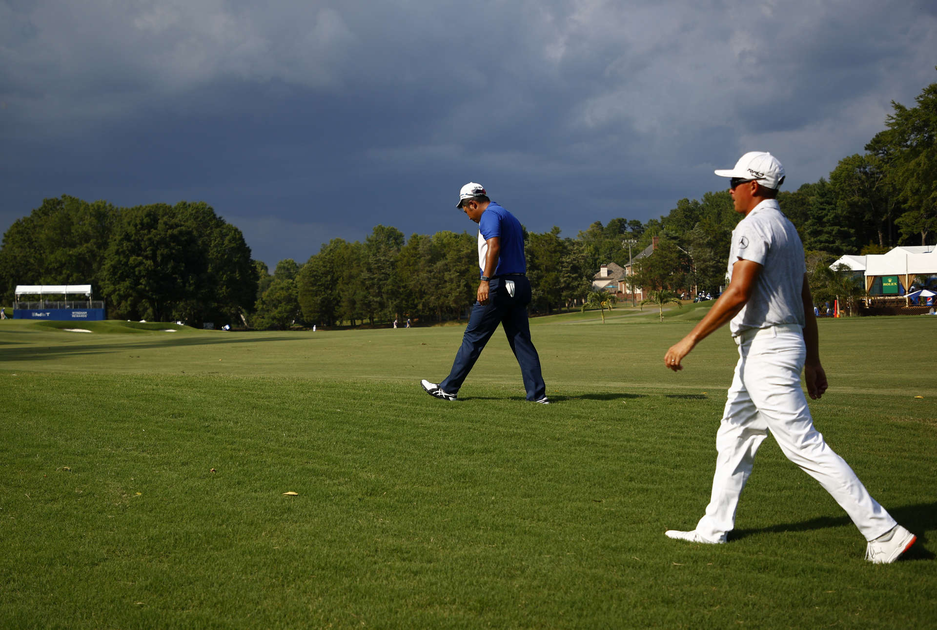 GREENSBORO, NORTH CAROLINA - AUGUST 12: Hideki Matsuyama of Japan and Rickie Fowler of the United States walk off the course on the 15th hole due to a weather delay during the first round of the Wyndham Championship at Sedgefield Country Club on August 12, 2021 in Greensboro, North Carolina. (Photo by Jared C. Tilton/Getty Images)