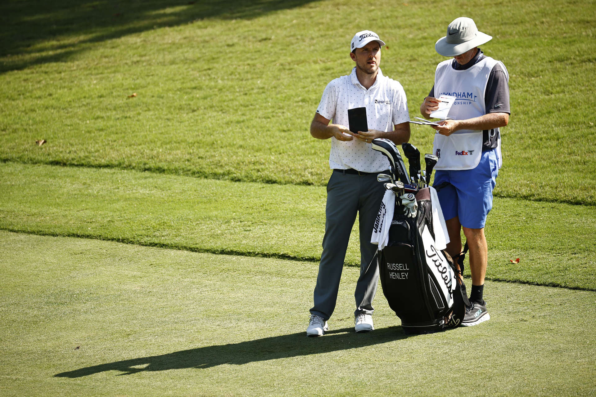 GREENSBORO, NORTH CAROLINA - AUGUST 13: Russell Henley of the United States waits with his caddie before hitting an approach shot on the 17th hole during the second round of the Wyndham Championship at Sedgefield Country Club on August 13, 2021 in Greensboro, North Carolina. (Photo by Jared C. Tilton/Getty Images)