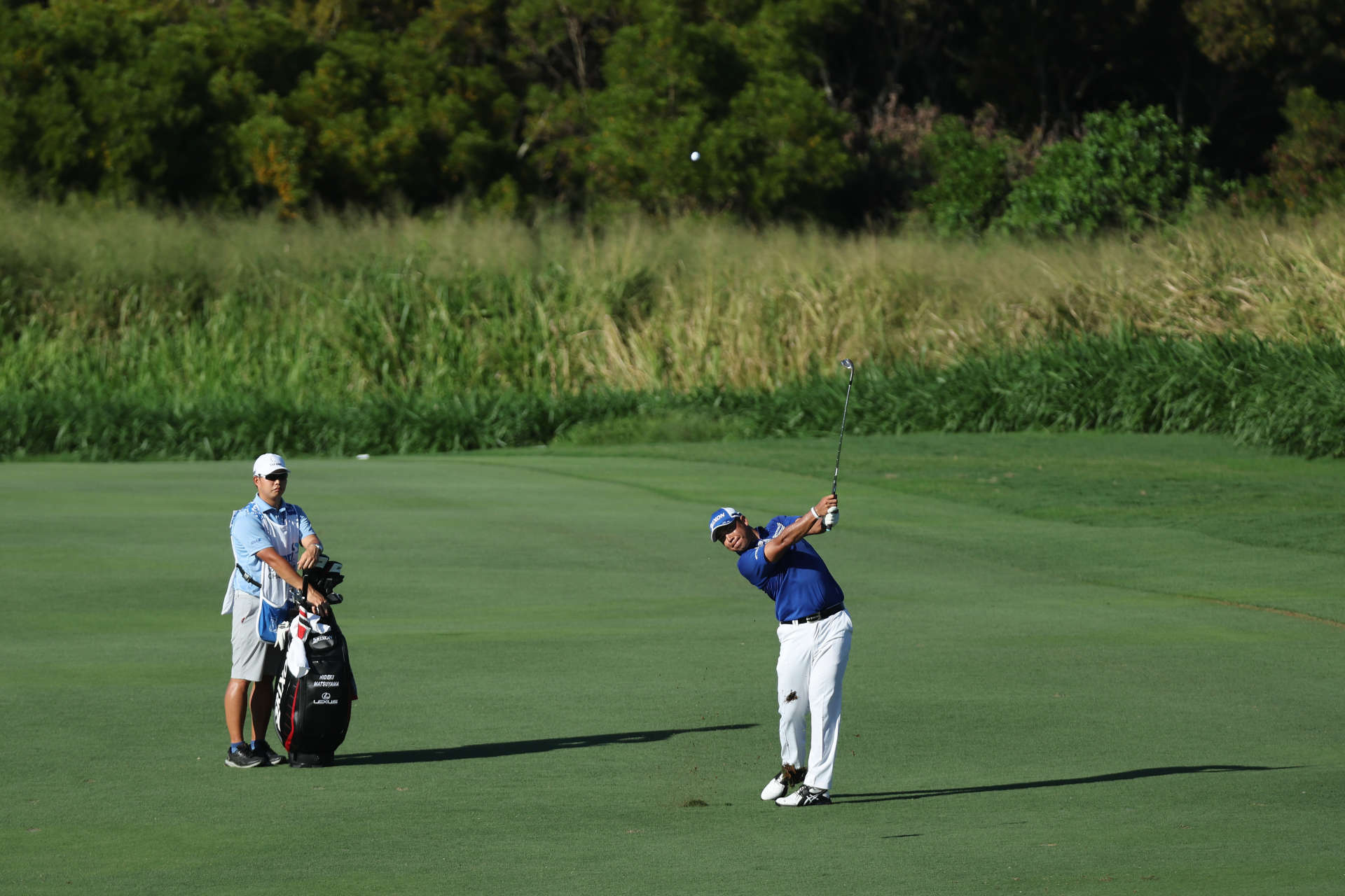 LAHAINA, HAWAII - JANUARY 08: Hideki Matsuyama of Japan plays an approach shot as caddie Shota Hayafuji looks on during the third round of the Sentry Tournament of Champions at the Plantation Course at Kapalua Golf Club on January 08, 2022 in Lahaina, Hawaii. (Photo by Gregory Shamus/Getty Images)