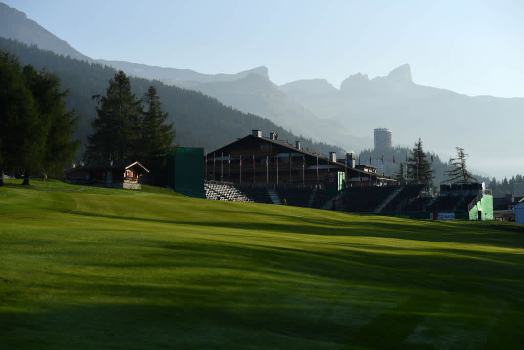 Der Blick auf das Grün von Loch 18. Im Hintergrund ragen die Alpen in die Höhe.