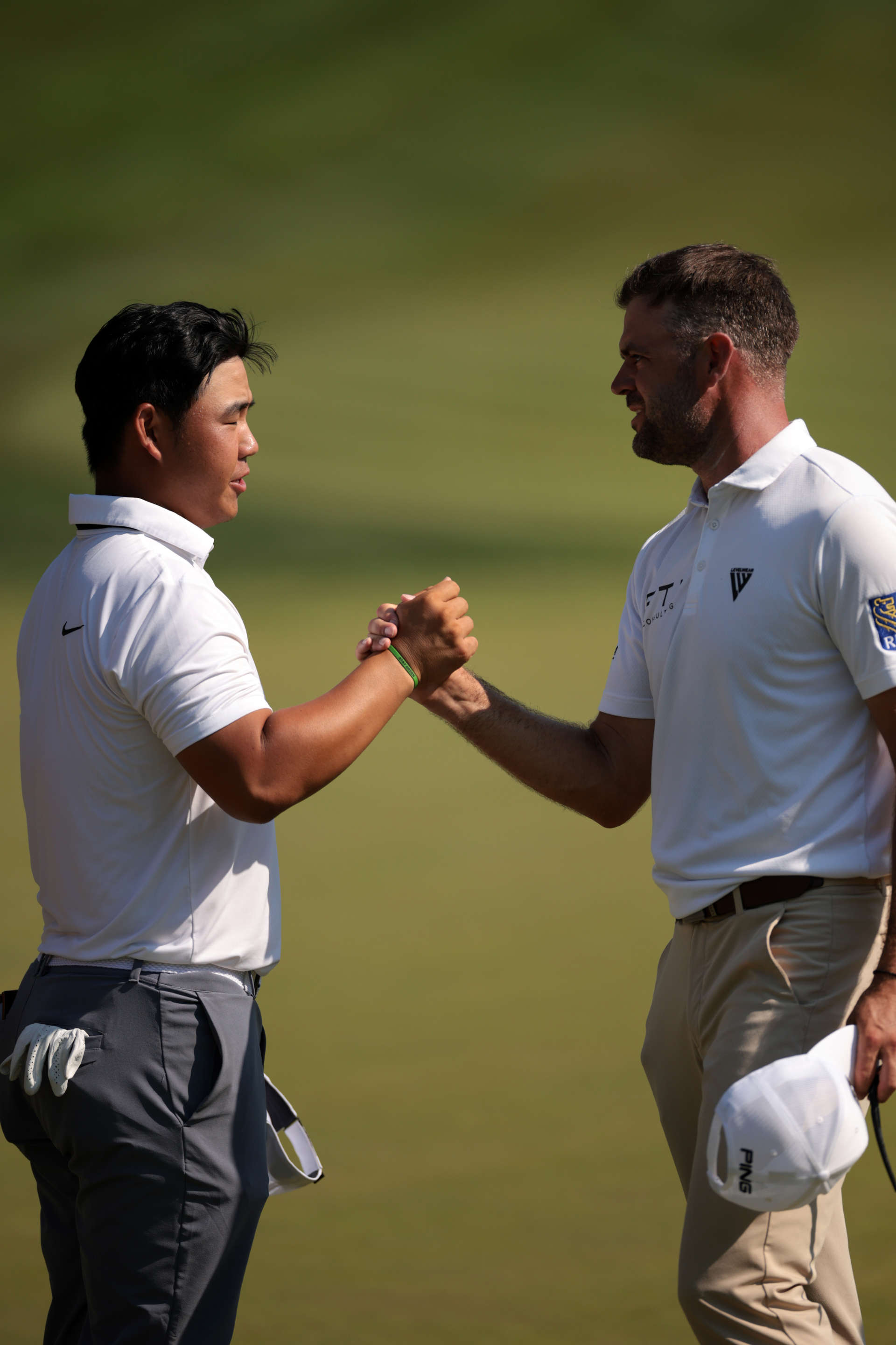 CROMWELL, CONNECTICUT - JUNE 20: Tom Kim of South Korea shakes hands with Corey Conners of Canada after their round on the 18th hole during the first round of the Travelers Championship at TPC River Highlands on June 20, 2024 in Cromwell, Connecticut. (Photo by James Gilbert/Getty Images)