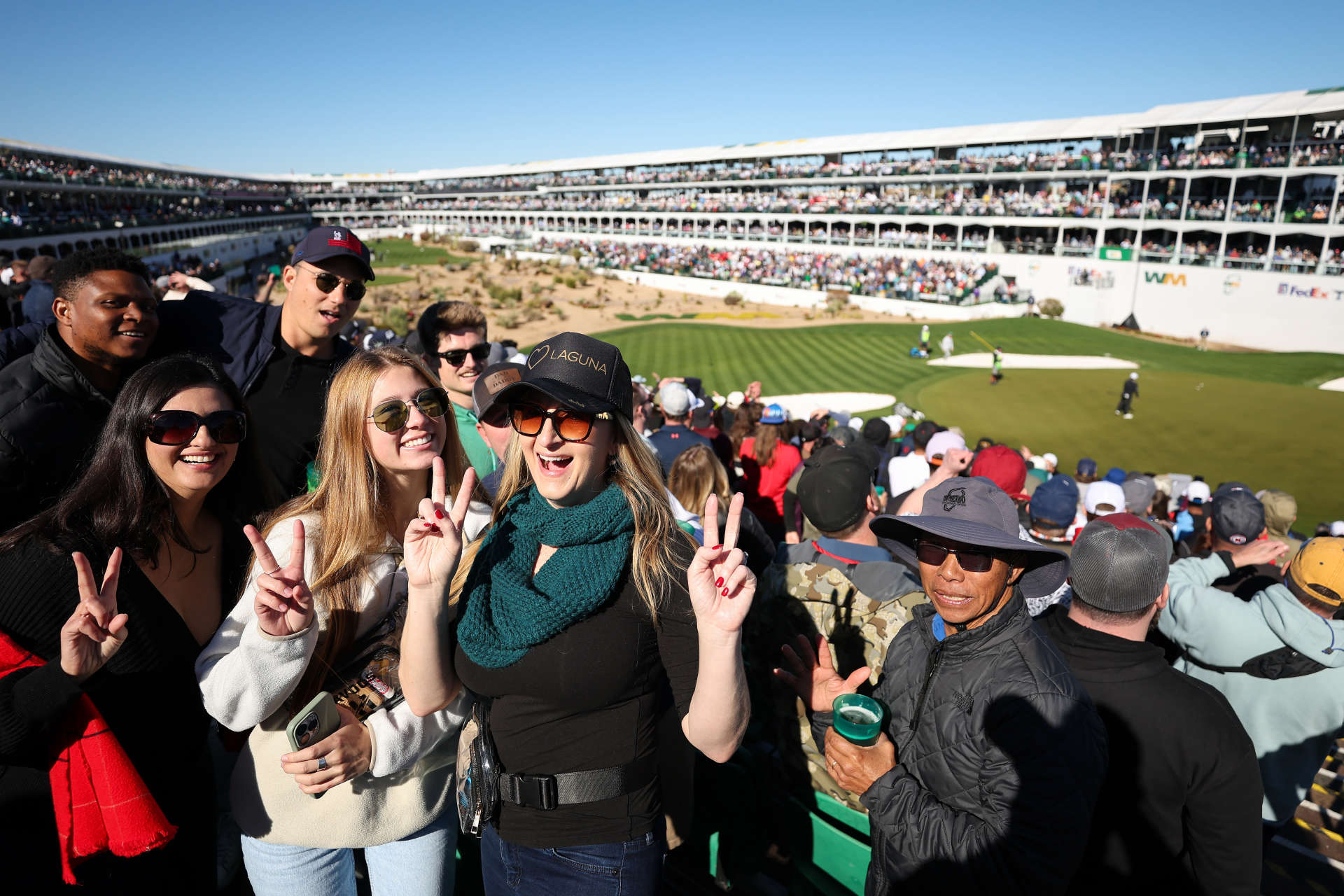 SCOTTSDALE, ARIZONA - FEBRUARY 11: Fans smile for a photo on the 16th green during the continuation of the third round of the WM Phoenix Open at TPC Scottsdale on February 11, 2024 in Scottsdale, Arizona. (Photo by Christian Petersen/Getty Images)