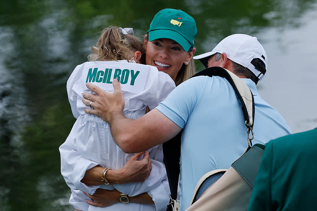 AUGUSTA, GEORGIA - APRIL 09: Rory McIlroy of Northern Ireland 
and his wife, Erica Stoll embrace their daughter, Poppy McIlroy after she holed out on the ninth green during the Par Three Contest prior to the 2025 Masters Tournament at Augusta National Golf Club on April 09, 2025 in Augusta, Georgia. (Photo by Harry How/Getty Images)
