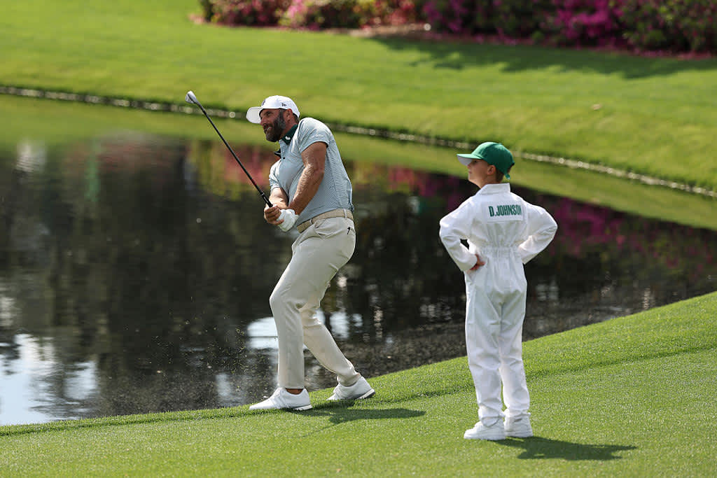 AUGUSTA, GEORGIA - APRIL 09: Dustin Johnson of the United States plays a shot as his son, Scott Johnson, watches during the Par Three Contest prior to the 2025 Masters Tournament at Augusta National Golf Club on April 09, 2025 in Augusta, Georgia. (Photo by Richard Heathcote/Getty Images)
