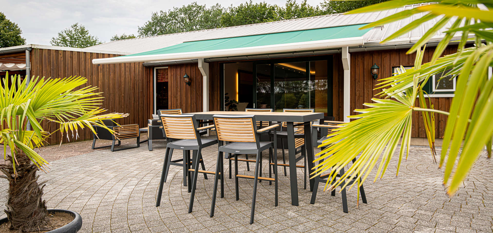 Gemütliche Terrasse beim Veranstaltungsraum im Golf Gut Glinde mit separaten Sitzbereichen und großer Markise – ideal für Meetings, Feierlichkeiten oder entspannte Pausen. Die komfortablen Sitzgelegenheiten und der geschützt-to- draußen machen diese Terrasse zum perfekten Ort für Veranstaltungen in entspannter Atmosphäre mit Blick auf die gepflegten Anlagen und die Natur unseres Golfplatzes.