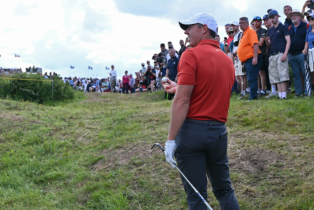 Northern Ireland's Rory McIlroy reacts after unearthing an old golf ball as he plays his own ball from the rough on the 11th hole on day three of the 153rd Open Championship at Royal Portrush golf club in Northern Ireland on July 19, 2025. (Photo by ANDY BUCHANAN / AFP) / RESTRICTED TO EDITORIAL USE (Photo by ANDY BUCHANAN/AFP via Getty Images)
