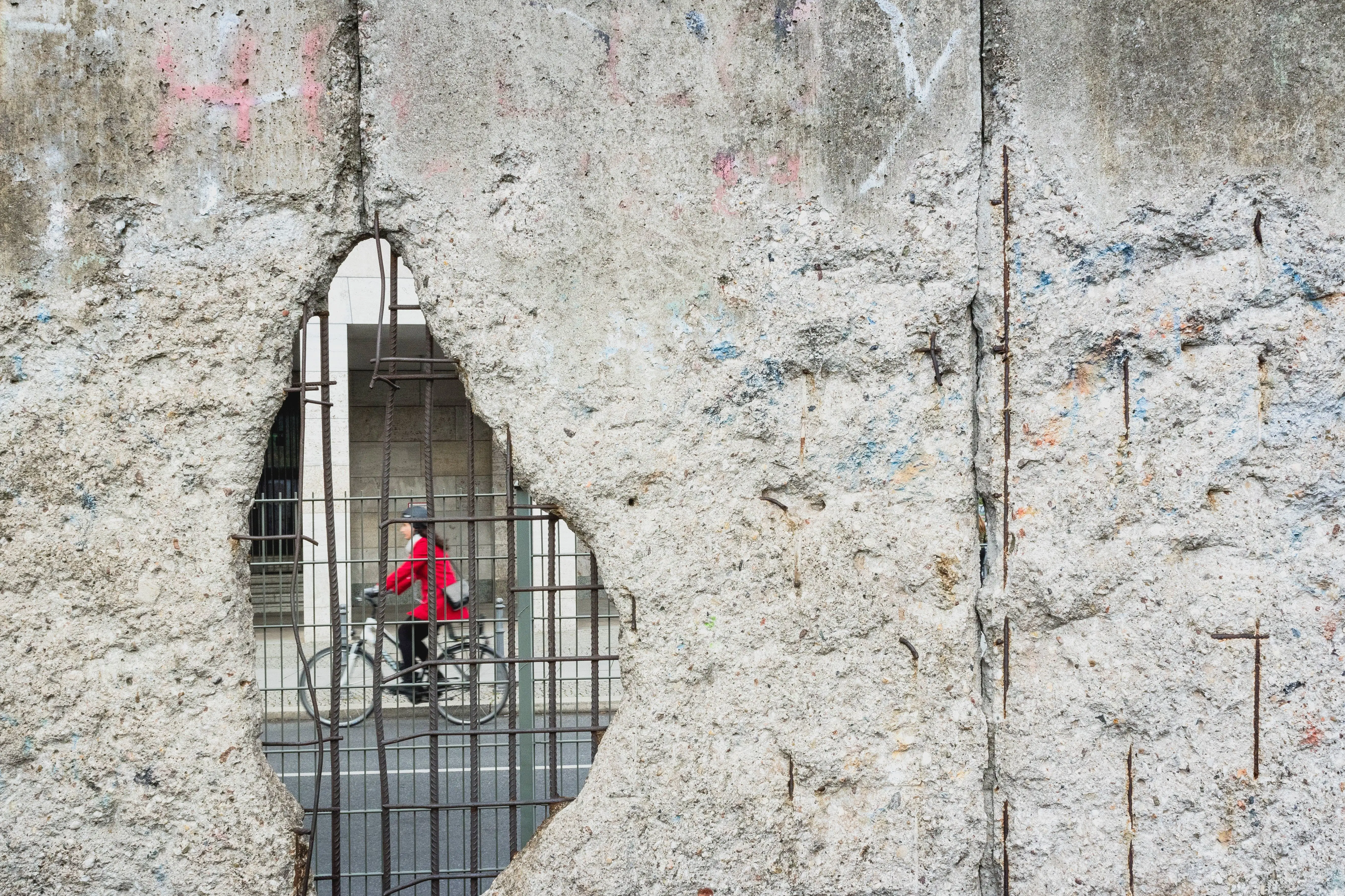 A Hole in the Old Berlin wall with a Cyclist Visible on the other Side