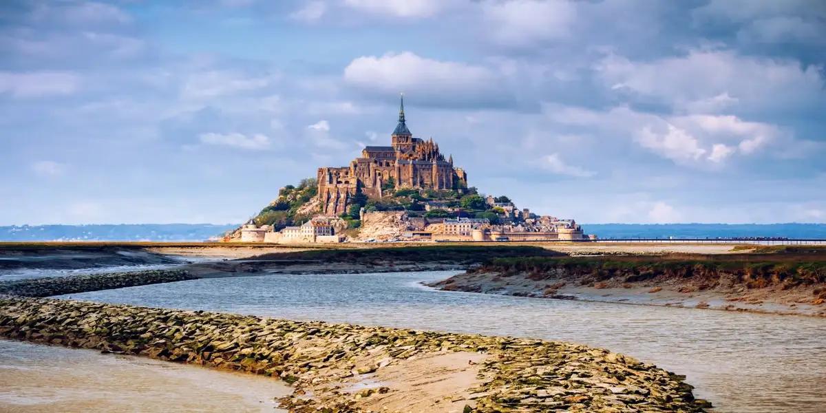 Mont-St.-Michele rises from the water under a blue sky