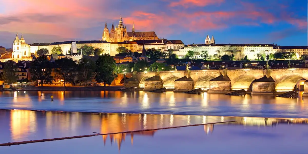 Vltava River in Prague at dusk with a view of the castle and Charles Bridge in the background