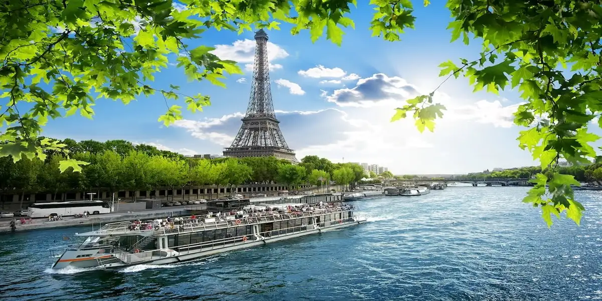 A boat cruises along the Seine River in Paris beneath the Eiffel Tower