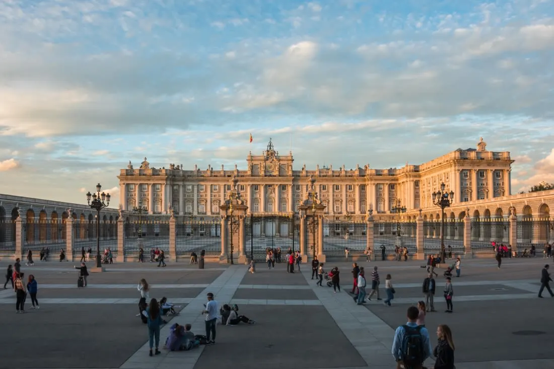 People rest in front of the Royal Palace of Madrid