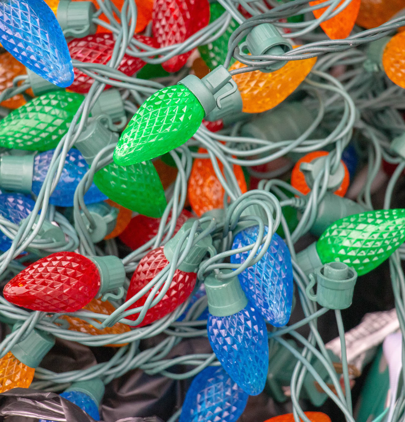 Multi-colored holiday lights sit in a pile.