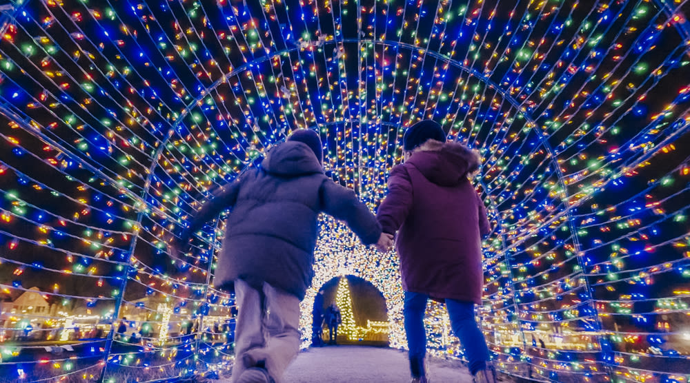 Children holding hands and running through a light tunnel