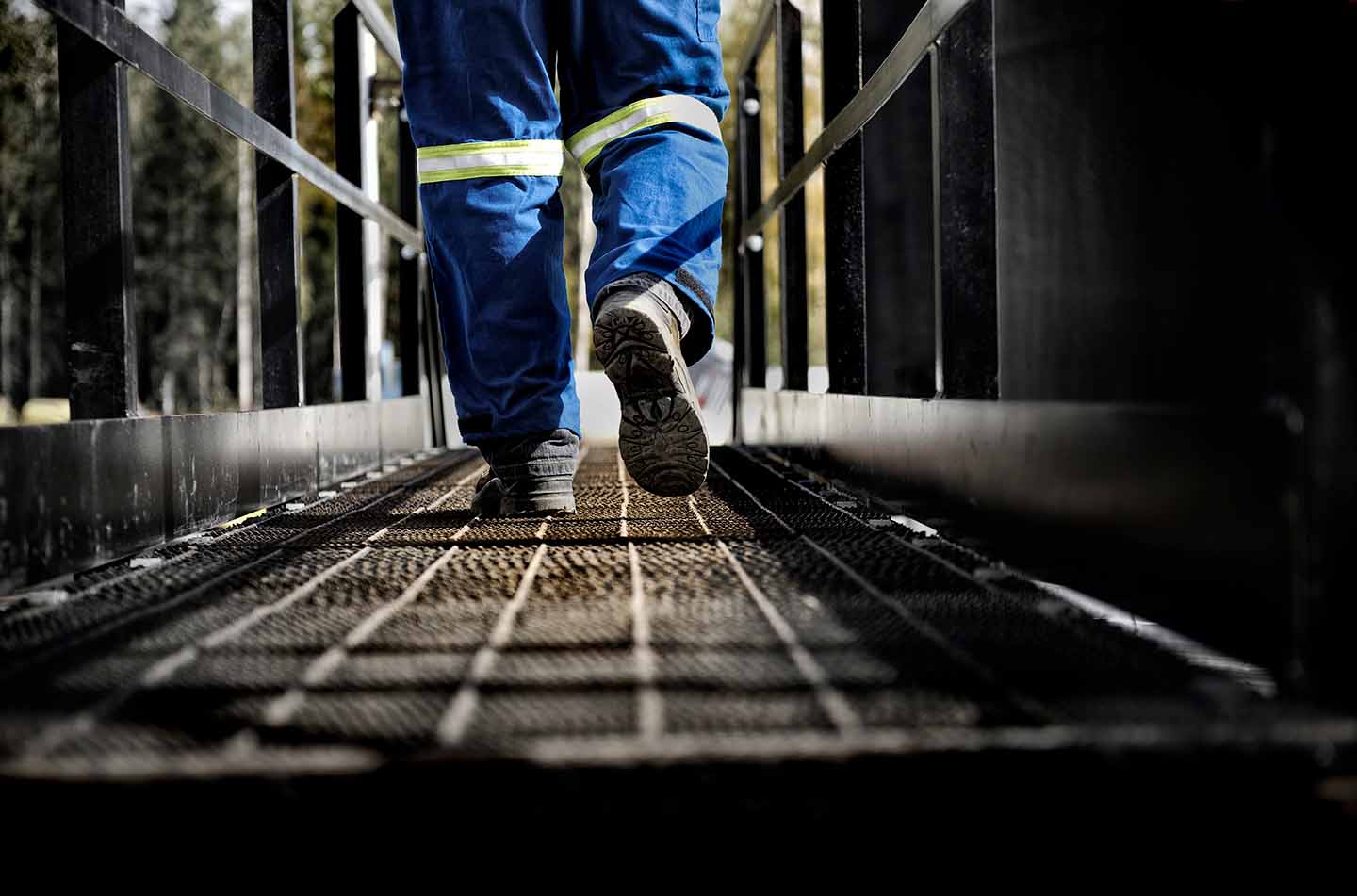 oil worker walking across a metal grate