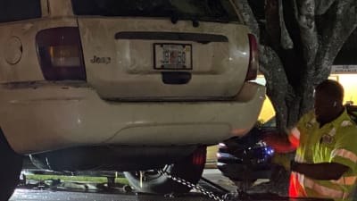 A tow truck driver secures a Jeep after officers found a body inside it in a canal on Thursday in Miramar.