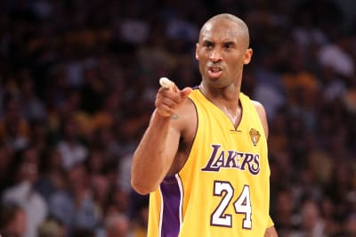 Kobe Bryant smiles and poses with a basketball wearing Laker home color  shoes and jersey at