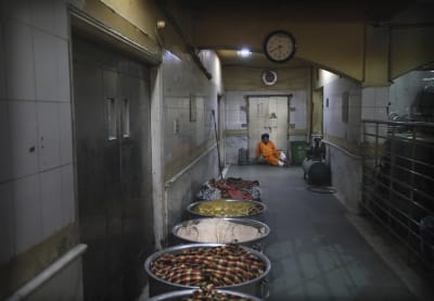 A cook in a Sikh kitchen cooking in an extremely large pot.