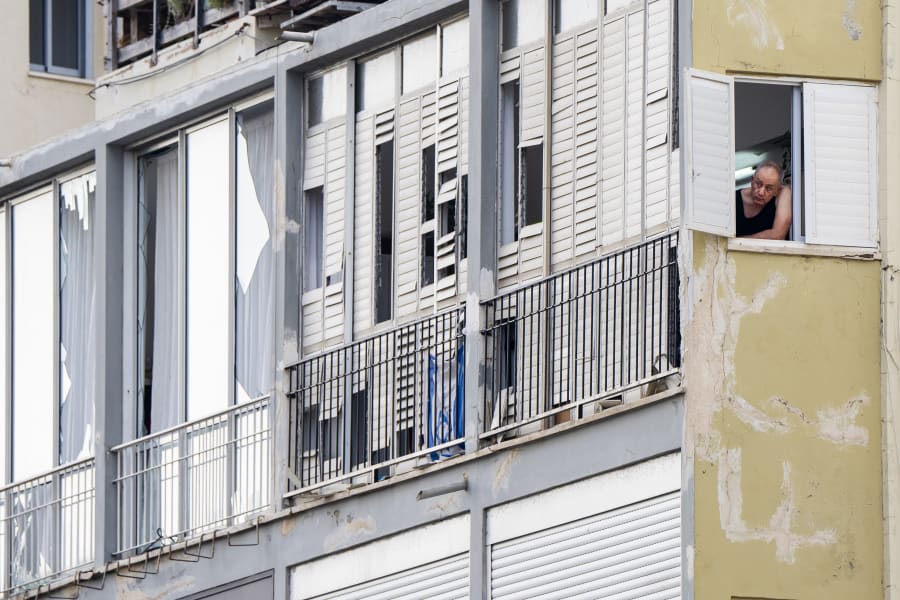 A man watches from his window at the scene of an explosive drone attack in Tel Aviv, Israel, Friday, July 19, 2024. Yemen's Houthi rebels claimed responsibility for a drone believed to have exploded above Tel Aviv early Friday morning. (AP Photo/Oded Balilty)