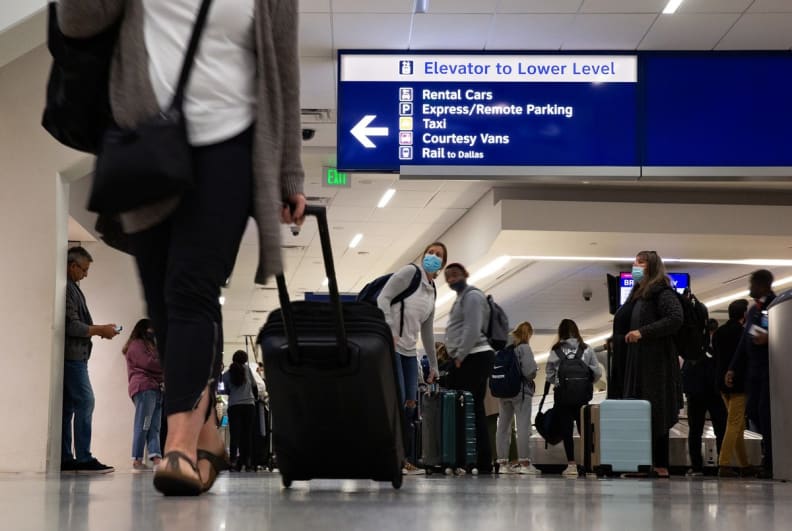 Travelers gather their luggage at baggage claim at the Dallas/Fort Worth International Airport on Nov. 18, 2021.