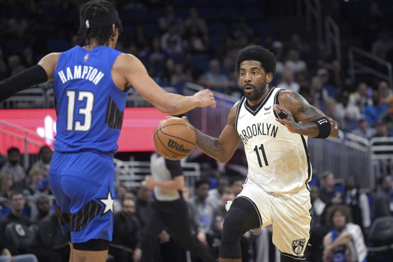 FILE - Brooklyn Nets guard Kyrie Irving (11), who is not permitted to play games in New York because he's unvaccinated for COVID-19, drives against Orlando Magic guard R.J. Hampton (13) during an NBA basketball game on Tuesday, March 15, 2022, in Orlando, Fla. Mayor Eric Adams will announce Thursday, March 23, 2022, that hes exempting athletes and performers from the citys vaccine mandate for private workers, a move that will allow Irving to play home games and unvaccinated baseball players to take the field when their season begins in a few weeks.  (AP Photo/Phelan M. Ebenhack, File)