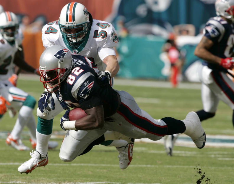 ARCHIVO - El ala cerrada de los New England Patriots Daniel Graham (82) es detenido por el apoyador de los Miami Dolphins Zach Thomas (54) en el primer cuarto durante un partido de fútbol americano de la NFL en Miami, en esta foto de archivo del domingo 10 de diciembre de 2006. Zach Thomas es finalista de 2021 para ingresar al Salón de la Fama del Fútbol Americano Profesional. (Foto AP / Lynne Sladky, archivo)
