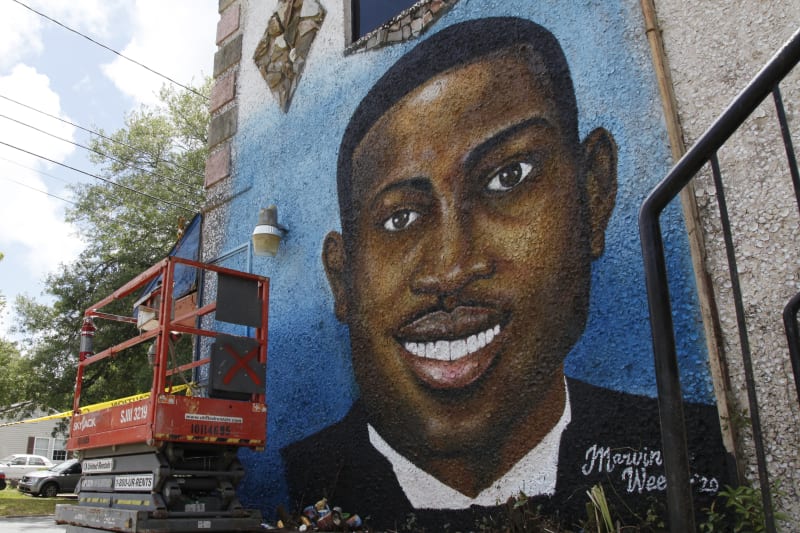 FILE - In this May 17, 2020, file photo, a recently painted mural of Ahmaud Arbery is on display in Brunswick, Ga., where the 25-year-old man was shot and killed in February. The white men convicted of hate crimes for chasing and killing Ahmaud Arbery as he ran in their Georgia neighborhood have been scheduled for sentencing this summer in federal court. U.S. District Court Judge Lisa Godbey Wood scheduled Aug. 1 sentencing hearings for all three men. Father and son Greg and Travis McMichael and their neighbor, William Roddie Bryan, each face a maximum penalty of life in prison. It's possible the sentencing date could change. Prosecutors asked the judge in a legal filing Tuesday, April 19, 2022 to postpone the hearings until later in August. (AP Photo/Sarah Blake Morgan, File)