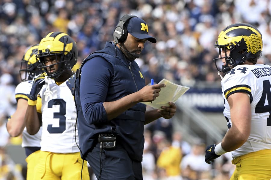 Michigan acting head coach Sherrone Moore looks over his play sheet during the first half of an NCAA college football game against Penn State, Saturday, Nov.11, 2023, in State College, Pa. (AP Photo/Barry Reeger)