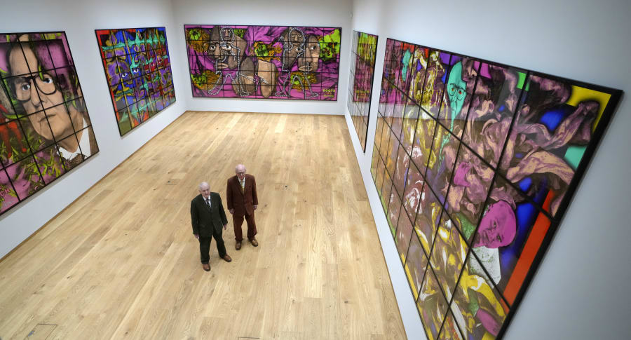 Gilbert and George stand with their artwork in their exhibition called The Paradisical Pictures at the opening of The Gilbert & George Centre in east London, Friday, March 24, 2023. (AP Photo/Kirsty Wigglesworth)