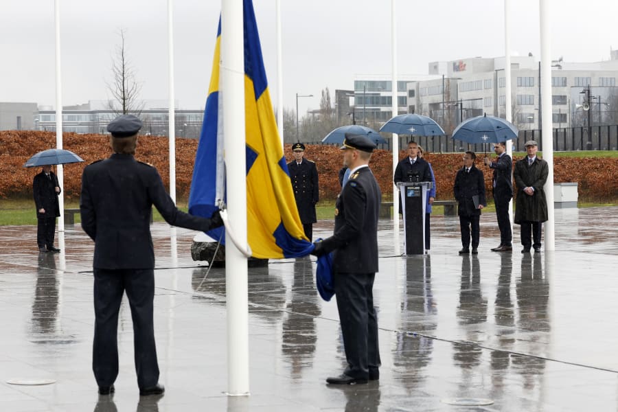 NATO Secretary General Jens Stoltenberg, center, speaks as members of the military prepare to raise the flag of Sweden during a ceremony to mark the accession of Sweden to NATO at NATO headquarters in Brussels, Monday, March 11, 2024. (AP Photo/Geert Vanden Wijngaert)