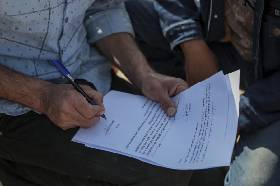 A supporter of the Shiite cleric Muqtada al-Sadr signs a pledge to stand against homosexuality or LGBTQ, outside a mosque in Kufa, Iraq, Friday, Dec. 2, 2022. Al-Sadr who announced his withdrawal from politics four months ago has broken a period of relative silence to launch an anti-LGBTQ campaign. (AP Photo/Anmar Khalil)