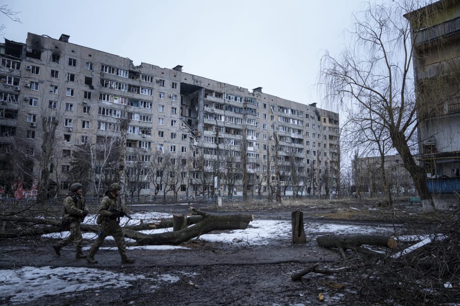 Ukrainian marine servicemen walk on a street in front of the residential building which was destroyed by Russian forces in the frontline city of Vuhledar, Ukraine, Saturday, Feb. 25, 2023. (AP Photo/Evgeniy Maloletka)