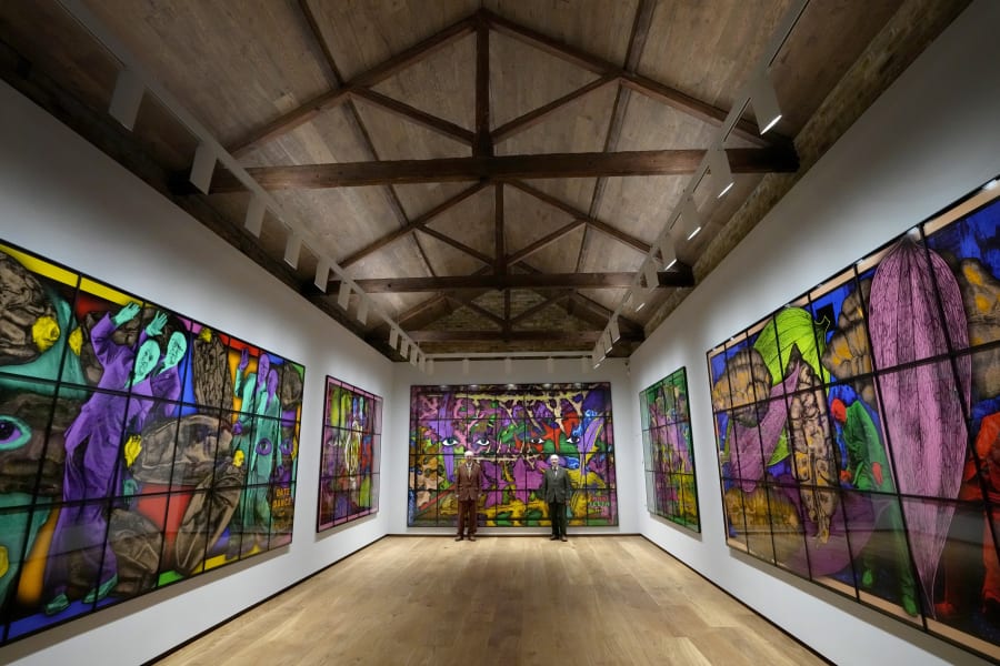Gilbert and George stand with their artwork in their exhibition called The Paradisical Pictures at the opening of The Gilbert & George Centre in east London, Friday, March 24, 2023. (AP Photo/Kirsty Wigglesworth)