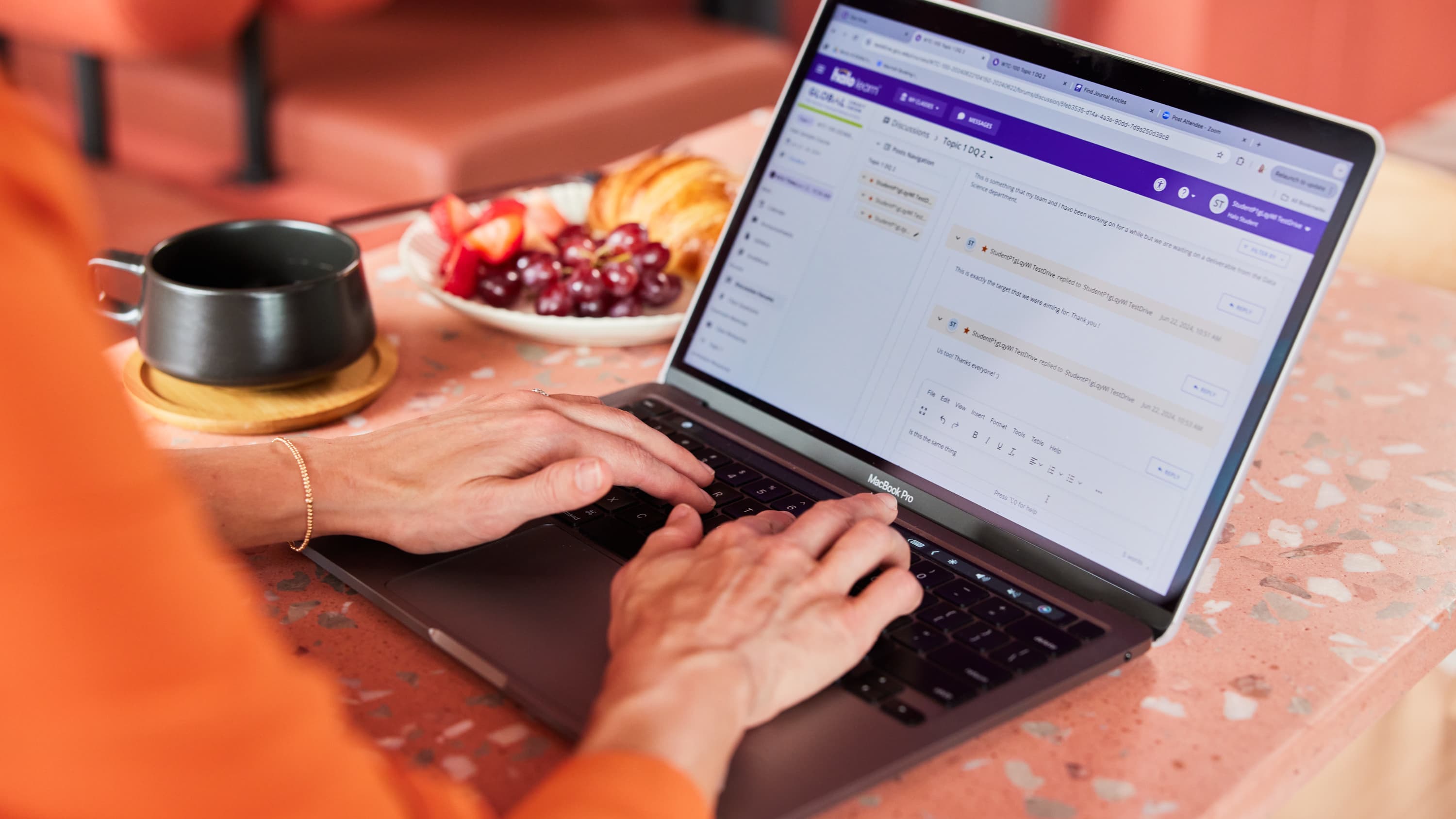Close up of hands typing on a laptop with online coursework on the screen