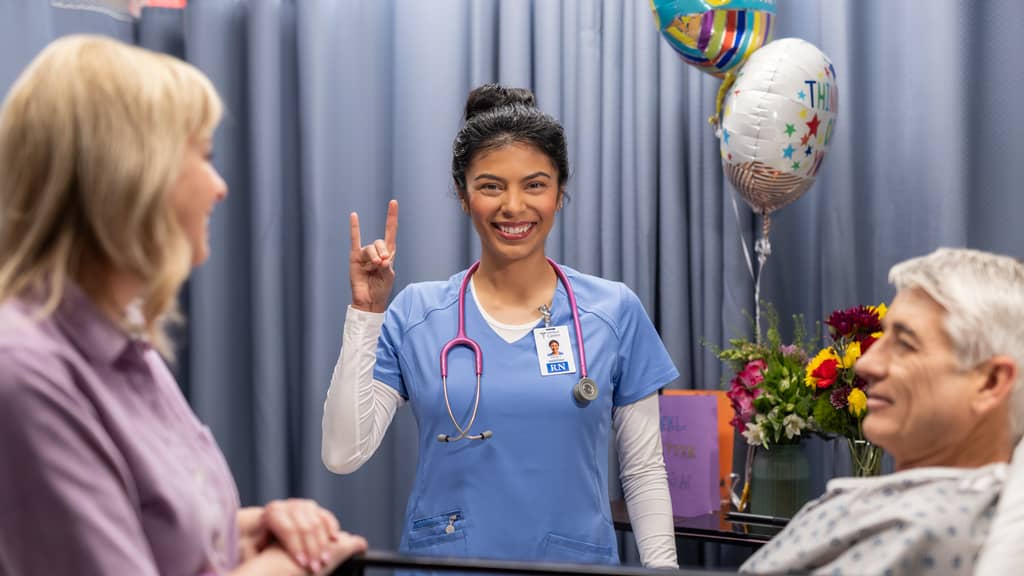 Nursing Student Giving Lopes Up Symbol and Smiling at Camera