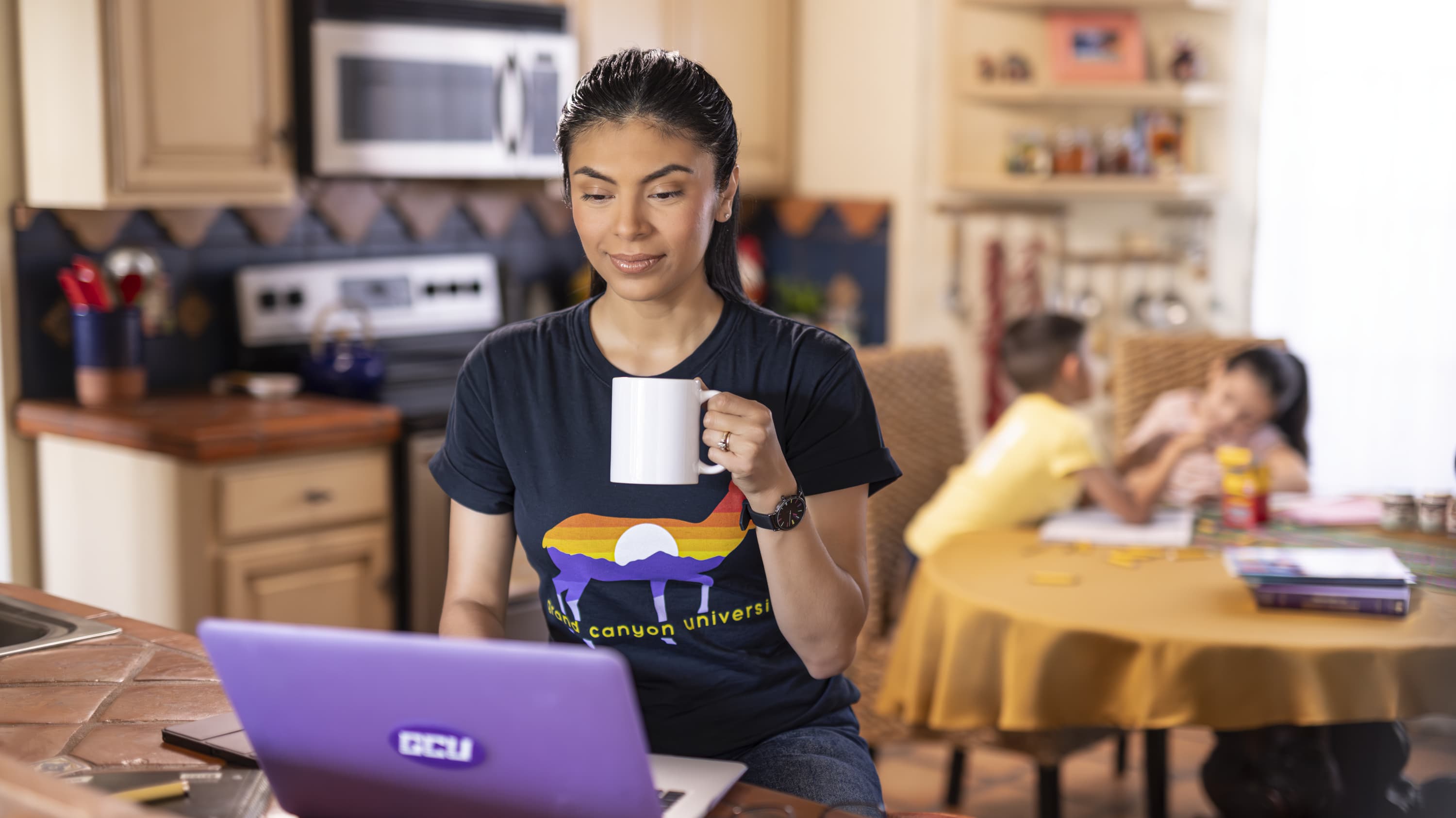 Women sipping drink and working on GCU laptop