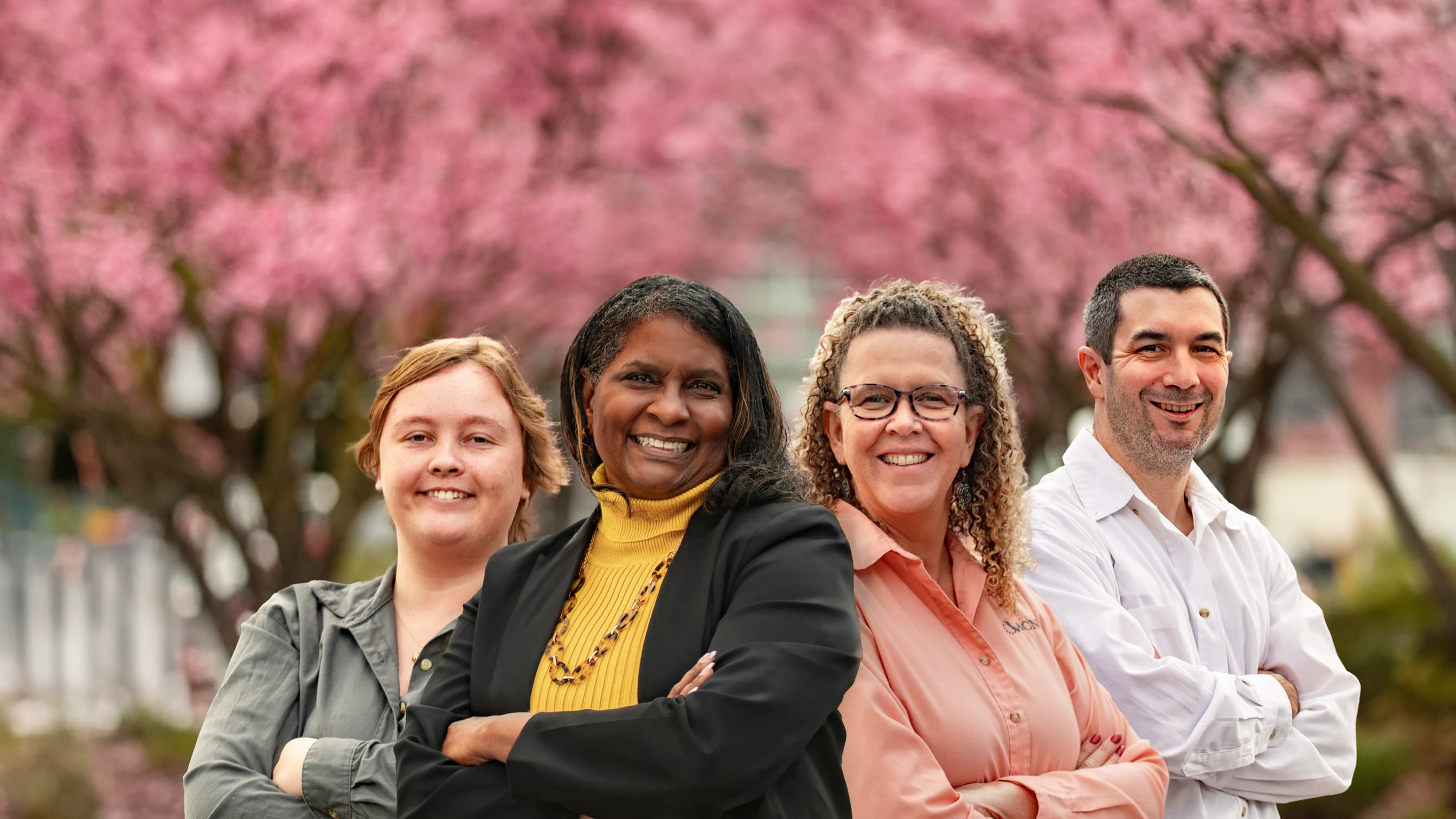 GCU admissions representatives smiling in front of cherry blossom tree