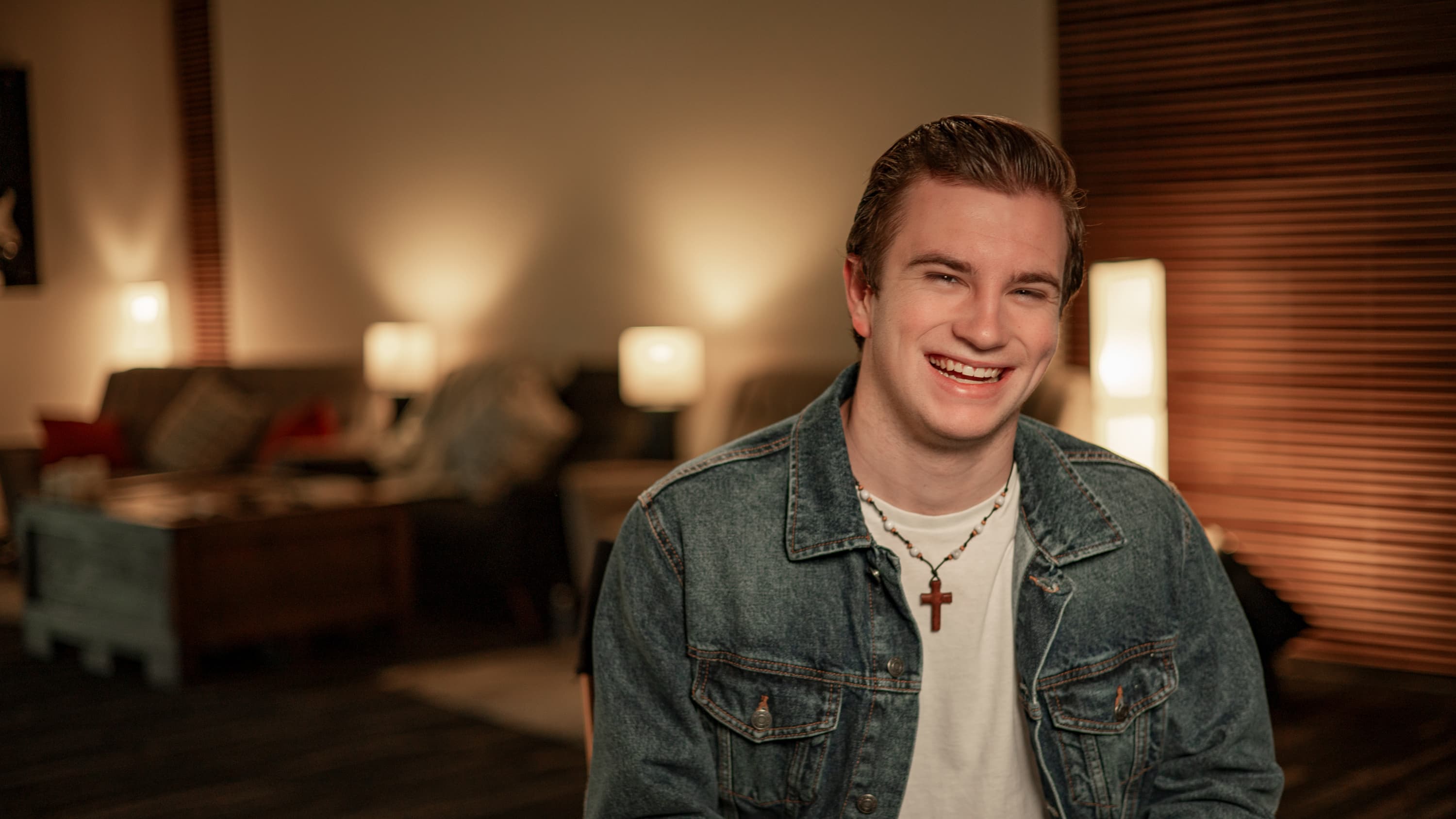 Male theology student smiling while sitting in a chair.