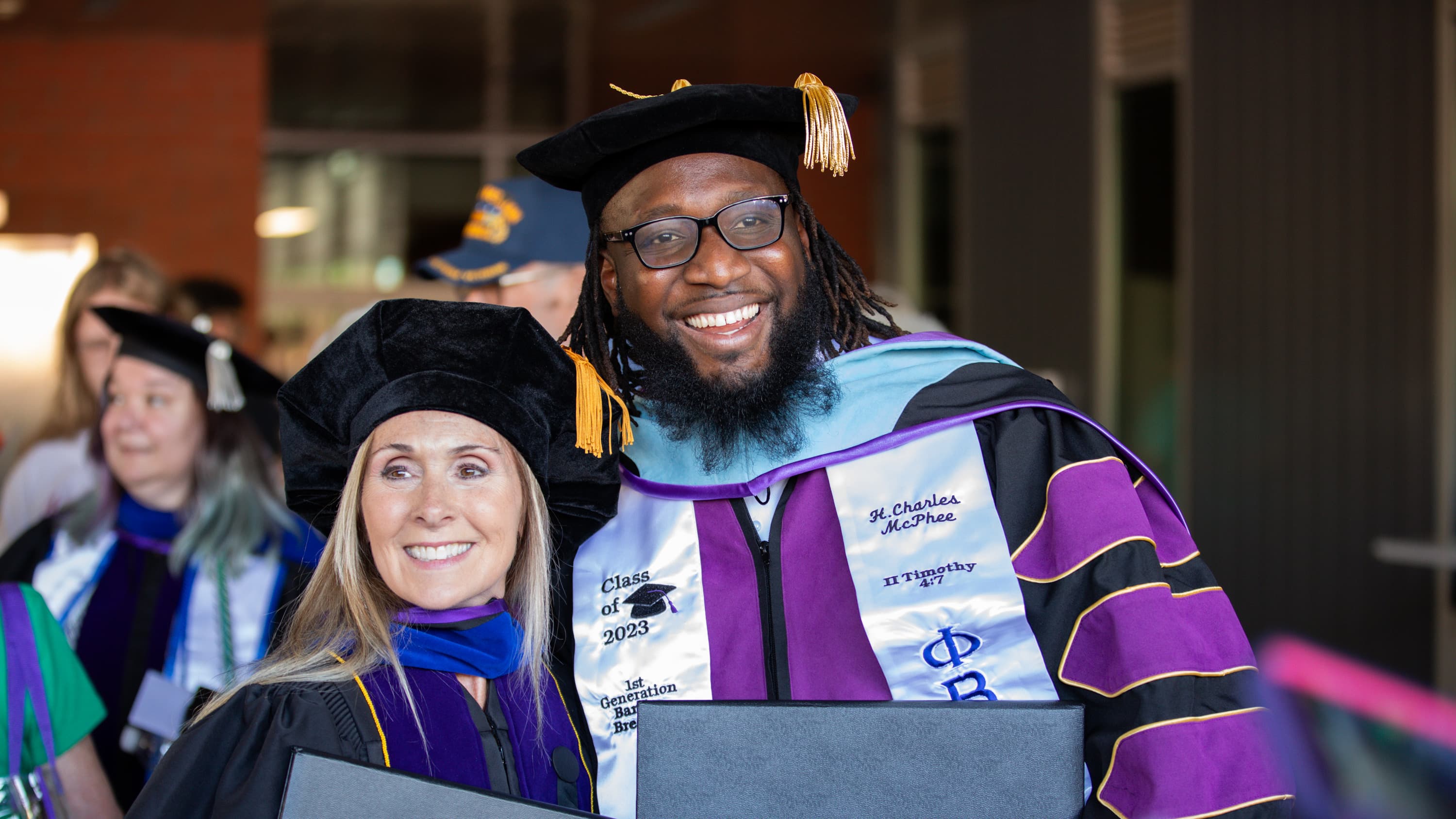 Male and female doctoral degree students smiling with diplomas at GCU Commencement